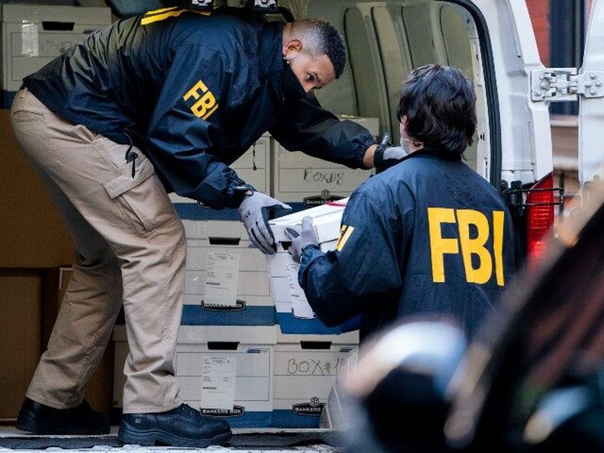 Federal agents load a vehicle with evidence boxes taken from a property related to Russian