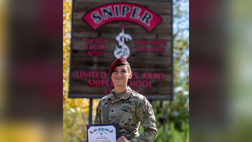 zoomed out shot of Sgt. Hay with sniper sign behind her