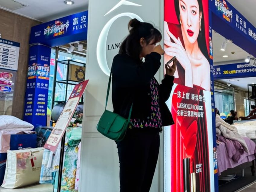 CHONGQING, CHINA - OCTOBER 22: A woman checks her makeup using her smartphone in front of