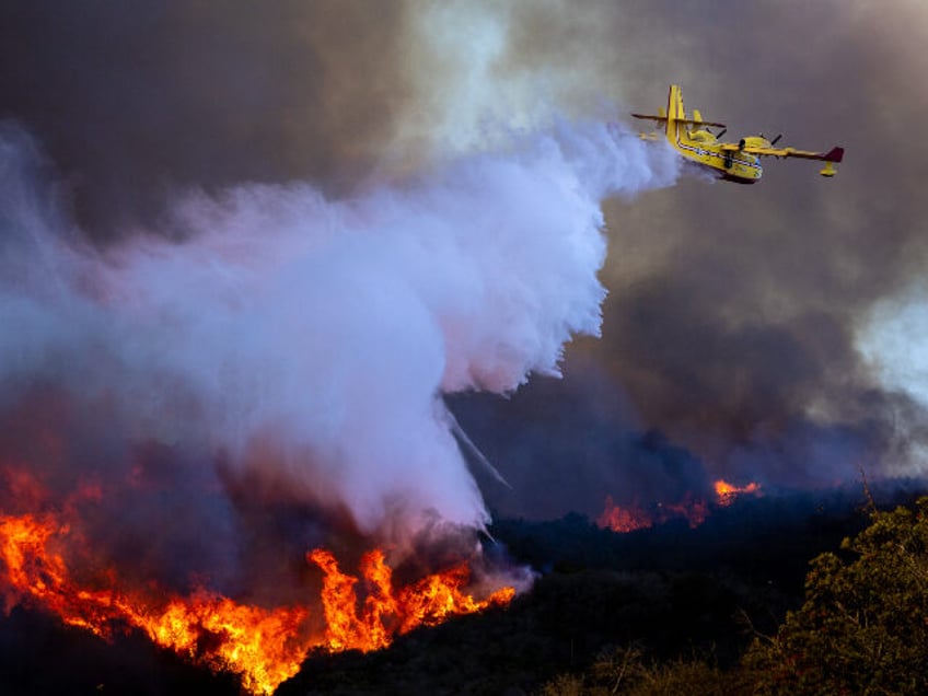 A Super Scooper drops ocean water on a hillside as the Palisades fire rages on Tuesday, Ja