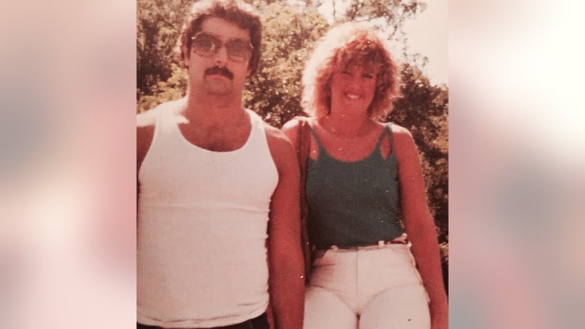 Ken Tekiela in a white tank top posing next to Holly wearing a green tank top and white shorts.