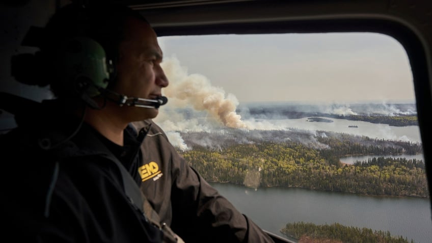 Manitoba Premier Wab Kinew surveys wildfires burning in northern Manitoba from a helicopter
