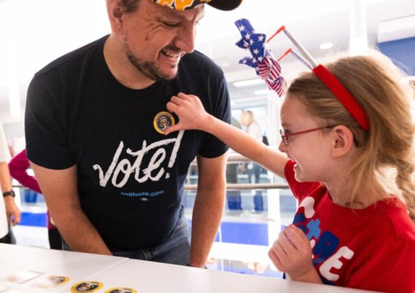 Nick Vucic gets an 'I Voted' sticker from his daughter Abigail, 7, after he casts his earl