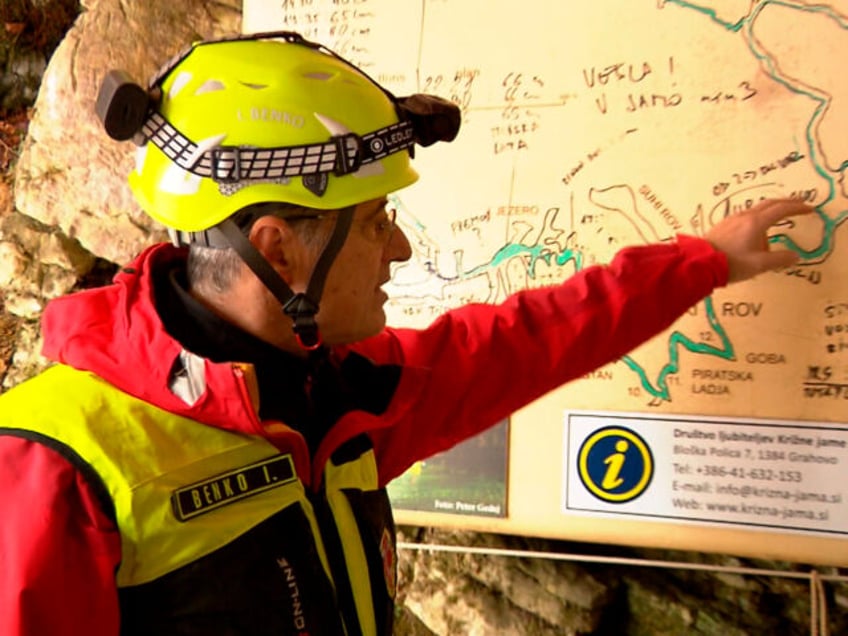 In this photo taken from video, a rescuer inspects the map of Krizna Jama cave near Grahovo, Slovenia, Sunday, Jan. 7, 2024. Slovenian authorities say five people are trapped in a cave in the southwest of the country because of high water levels caused by heavy rainfall. The group includes …