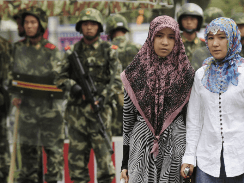 Two ethnic Uighur women pass Chinese paramilitary policemen standing guard outside the Grand Bazaar in the Uighur district of the city of Urumqi in China's Xinjiang region on July 14, 2009. A mosque was closed and many businesses were shuttered a day after police shot dead two Muslim Uighurs, as ethnic tensions simmered in restive Urumqi. AFP PHOTO / Peter PARKS (Photo credit should read PETER PARKS/AFP/Getty Images)