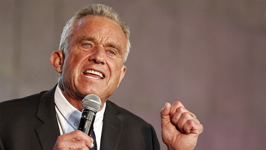 Robert F. Kennedy, Jr. holding microphone with right hand gesturing with left