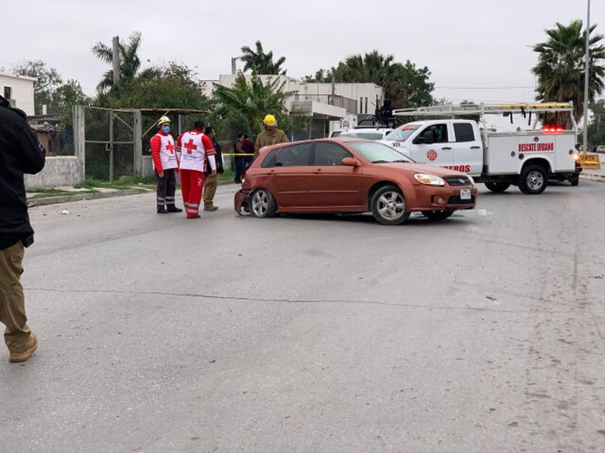 Emergency personnel try to remove the body of a crash victim from a vehicle struck by flee