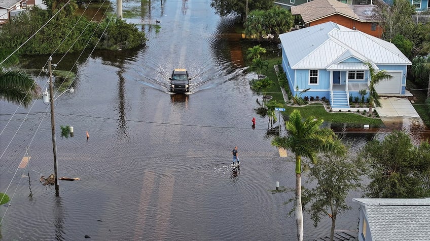 In this aerial view, a person walks through flood waters that inundated a neighborhood after Hurricane Milton came ashore