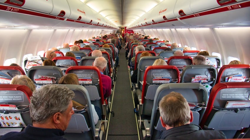 plane cabin from behind half full with passengers