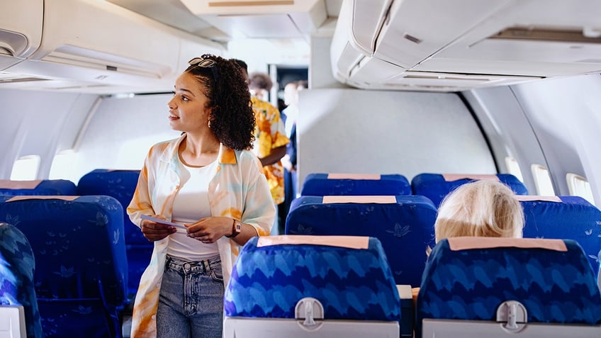 woman searching for seat on plane