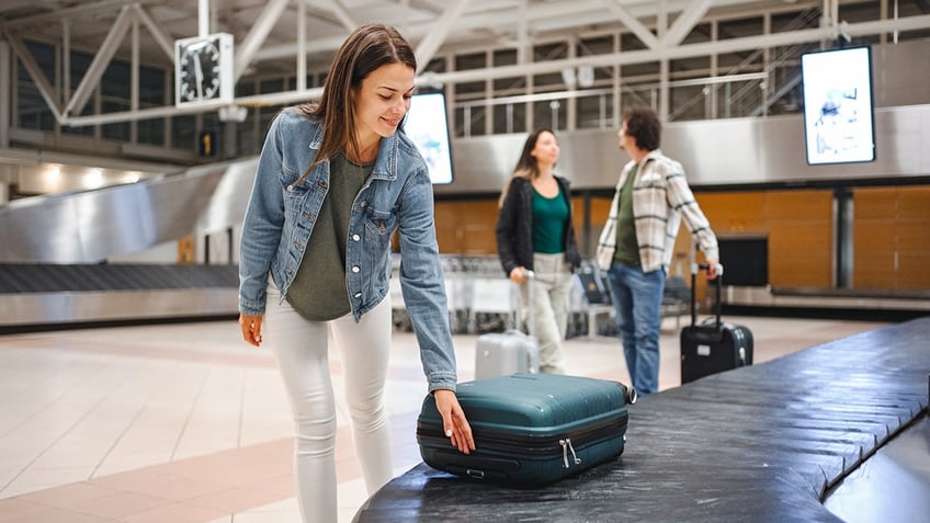 woman grabbing luggage at baggage claim