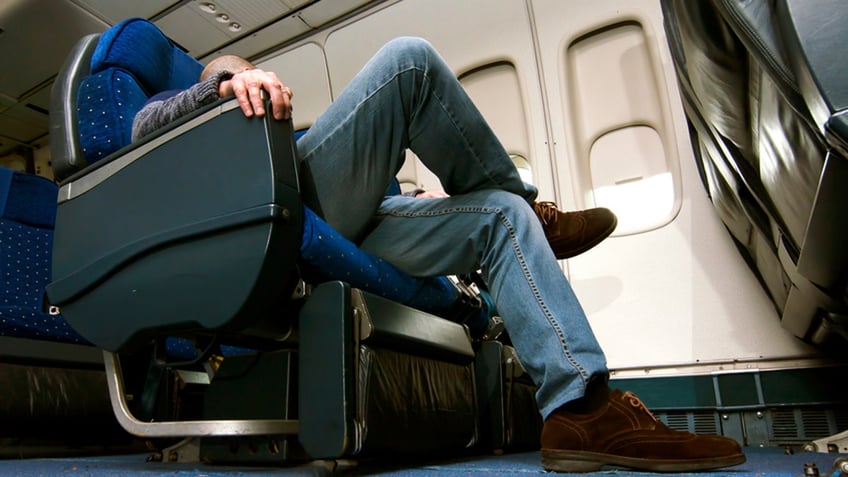 passenger sits with legs crossed on airplane