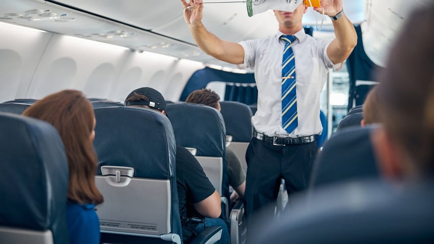 Steward demonstrating safety procedure prior to commercial airline flight took off