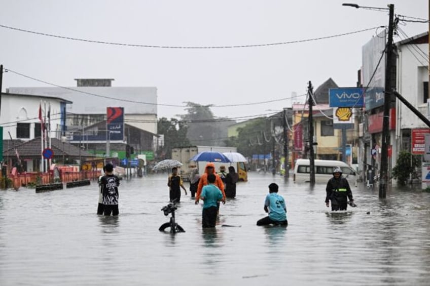 People wade through a flooded street during heavy rain in Pasir Puteh in Malaysia's Kelant