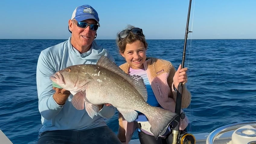 Captain Dale Bittner and 12-year-old Julia Berstein holding red grouper