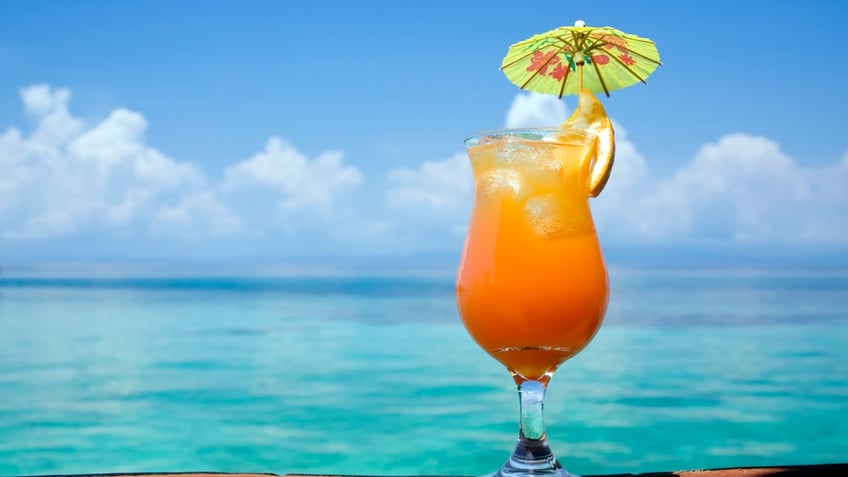 A refreshing drink, with a tropical paradise in the background