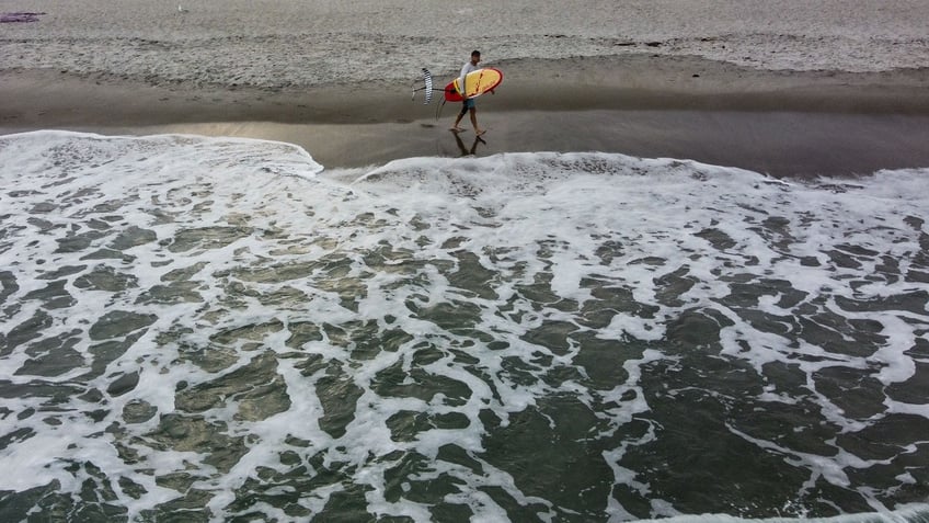 A surfer walks on Cocoa Beach, Florida