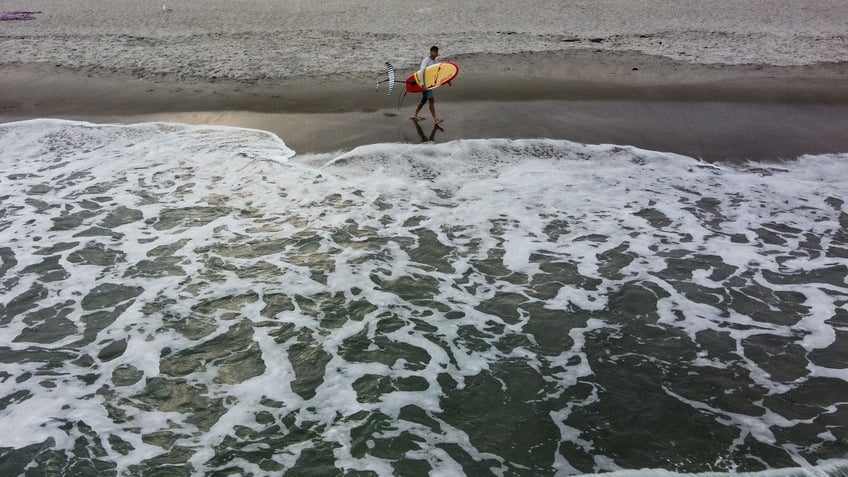 A surfer walks on Cocoa Beach, Florida