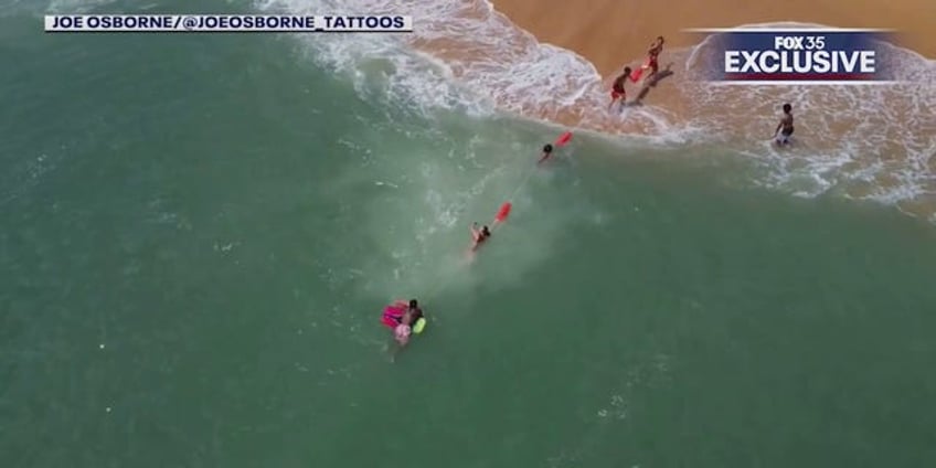 florida lifeguards form human chain to rescue boogie boarder drone video shows