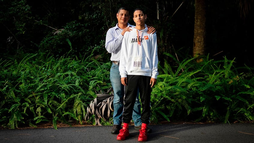 Father and son pose for photo outdoors.