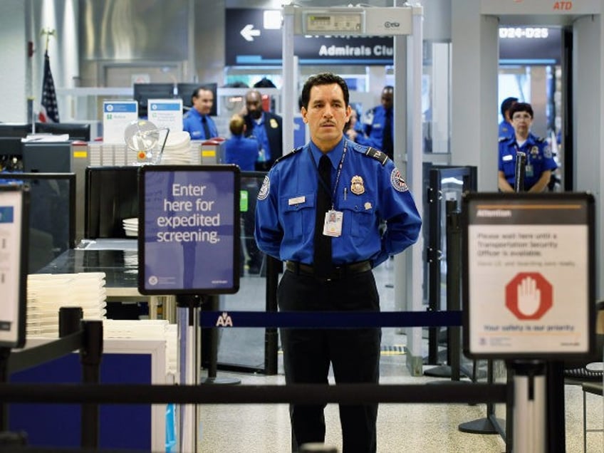 A TSA agent waits for passengers to use the TSA PreCheck lane being implemented by the Tra