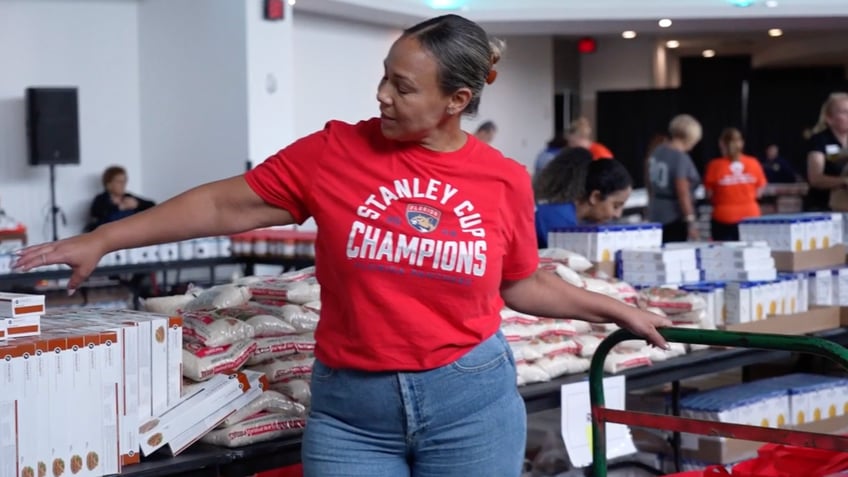 A volunteer wearing a shirt celebrating the Panthers winning the Stanley Cup is seen sorting food collected as part of the "Goals for Food" program.