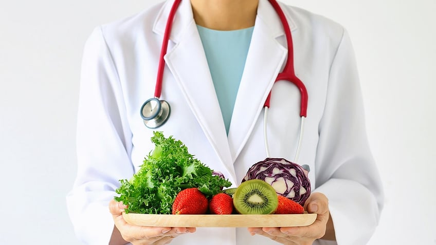 Photo of doctor holding plate of fruits and vegetables