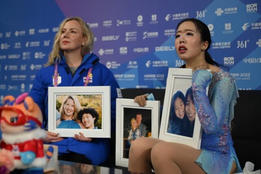 Thailand’s Teekhree Silpa-Archa (R) holds the photos of US figure skaters who died in th