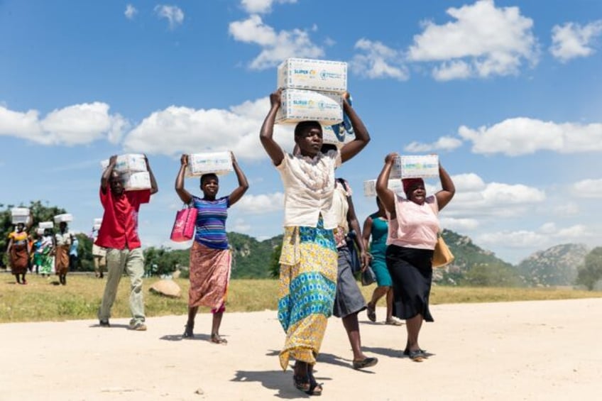 Mothers carry boxes of porridge backed by US aid in the Mutokoarea of Zimbabwe in 2019 as