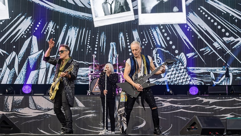 Vivian Campbell, Joe Elliott and Phil Collen from Def Leppard perform on stage