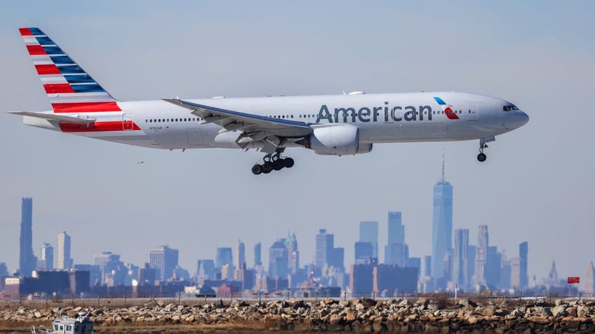 An American Airlines jet lands at JFK Airport in New York with the skyline in the background