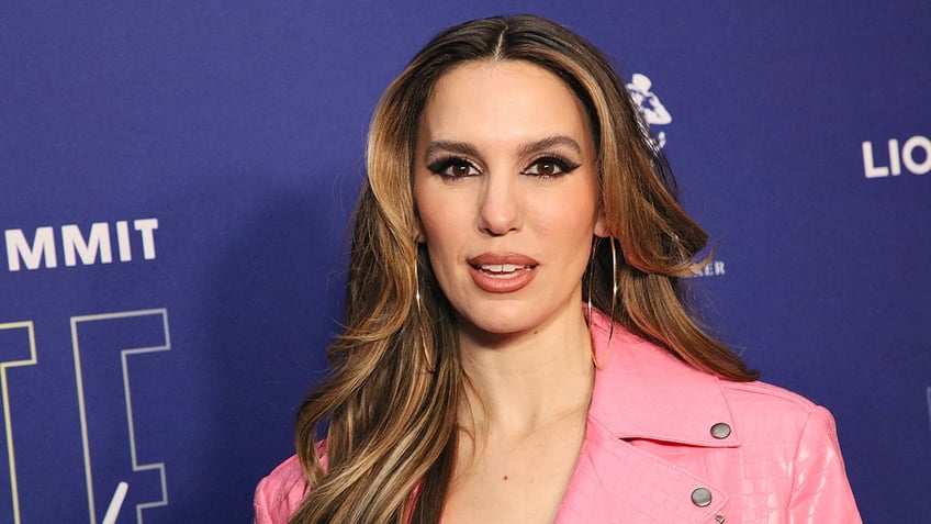 Christy Carlson Romano in a pink leather jacket looks directly at the camera on the carpet