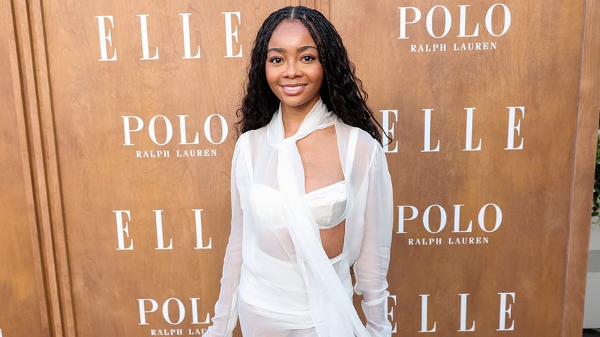 Skai Jackson in a white bra and see-through white top smiles on the carpet