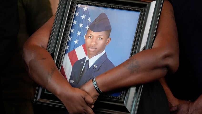 Roger Fortson's mother holding a photo of him