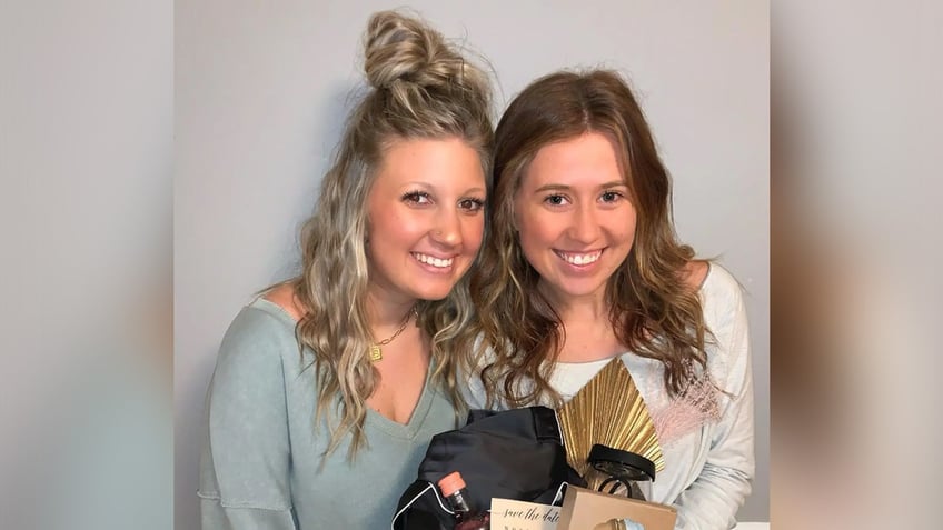 Two women pose with a basket of goodies.