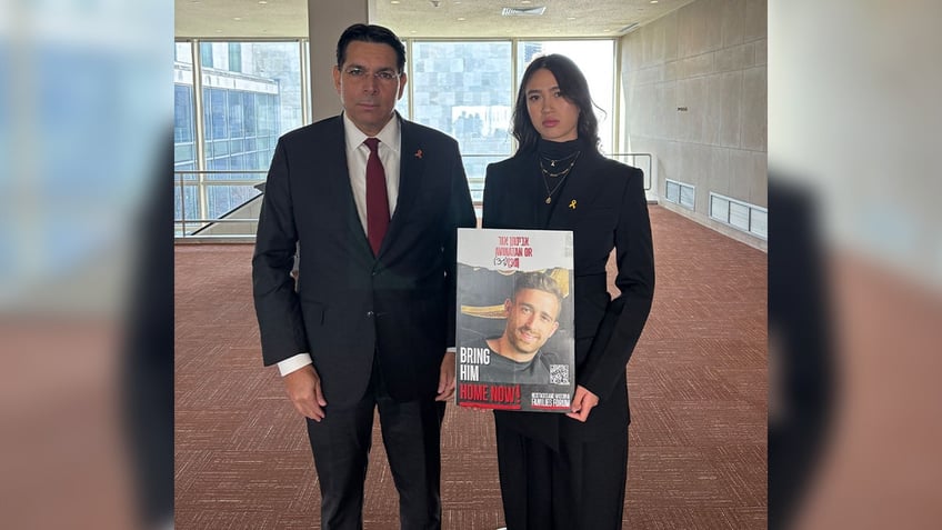 Israeli U.N. Ambassador Danny Danon stands next to Noa Argamani who is holding a poster of her partner who is still in Hamas captivity