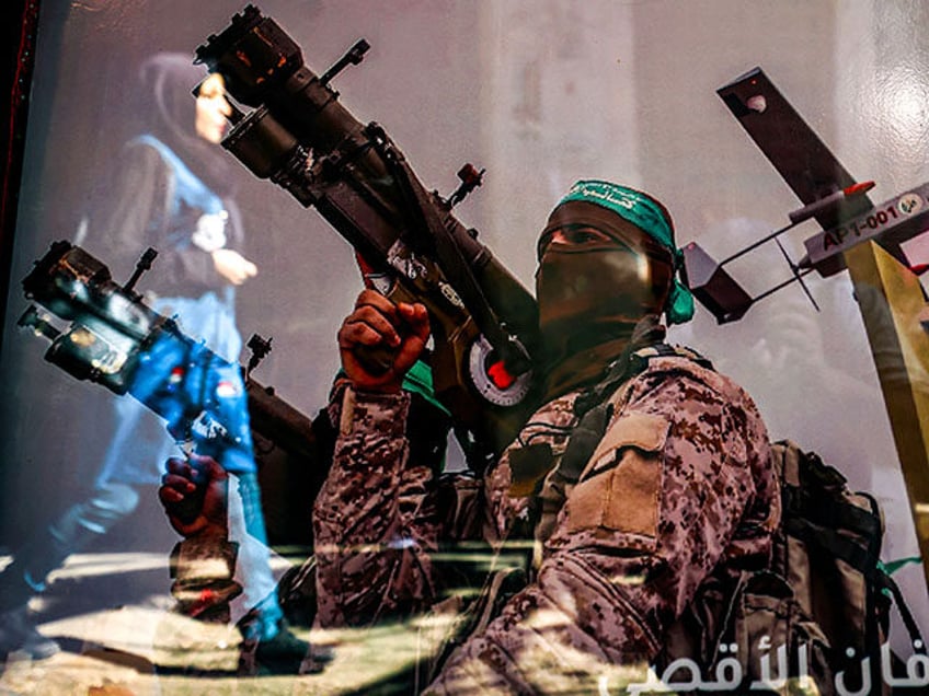 A reflection shows a woman walking past a poster in a shop window showing a fighter of the