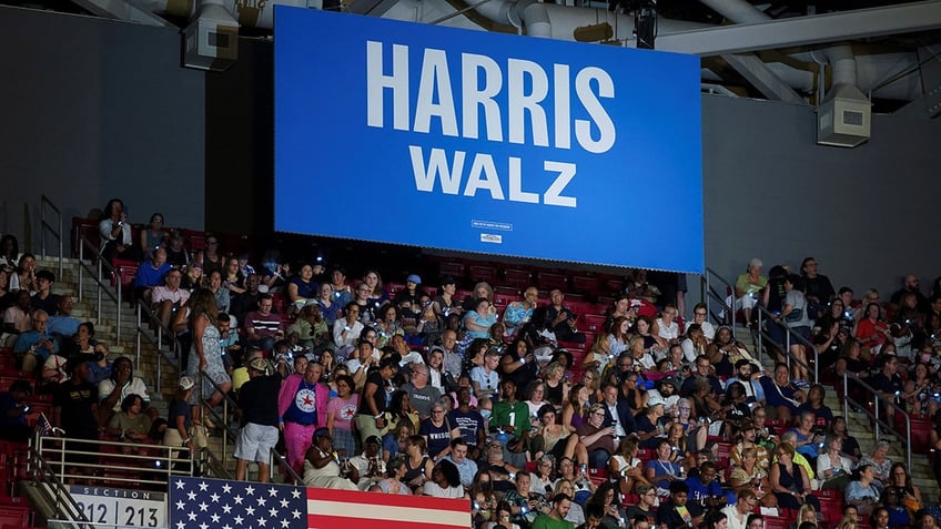 rallygoers seated in bleachers at Harris-Walz event