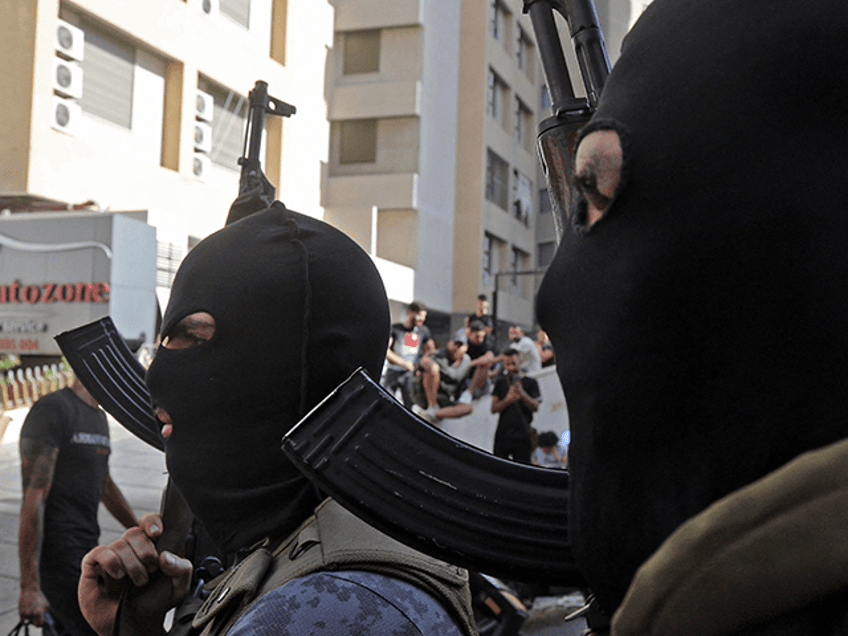 Masked Shiite fighter from Hezbollah and Amal movements walk with Kalashnikov assault rifl