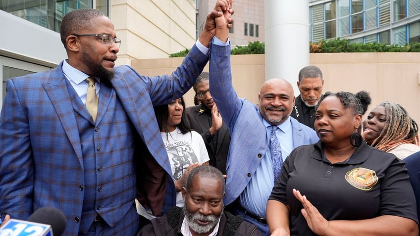 Civil lead counsel Malik Shabazz, left, raises the hand of co-counsel Trent Walker