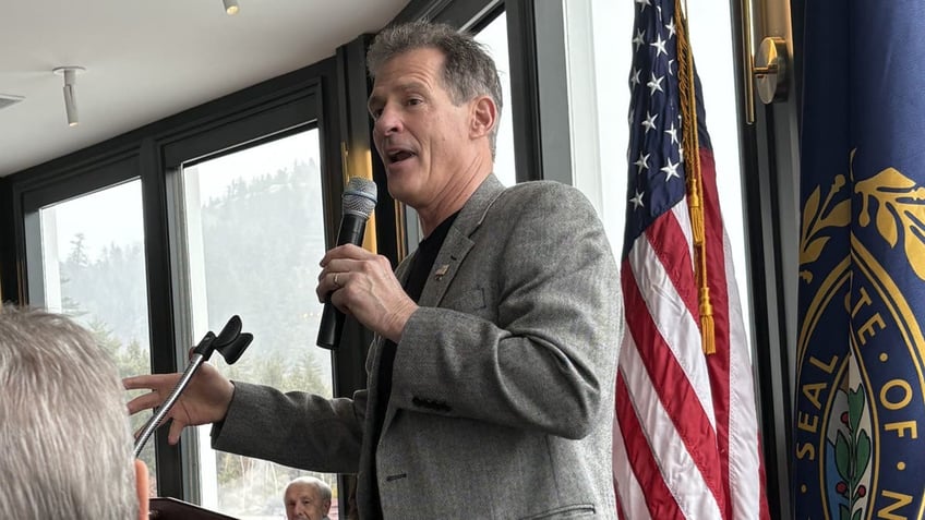 scott brown holding microphone, flags behind him