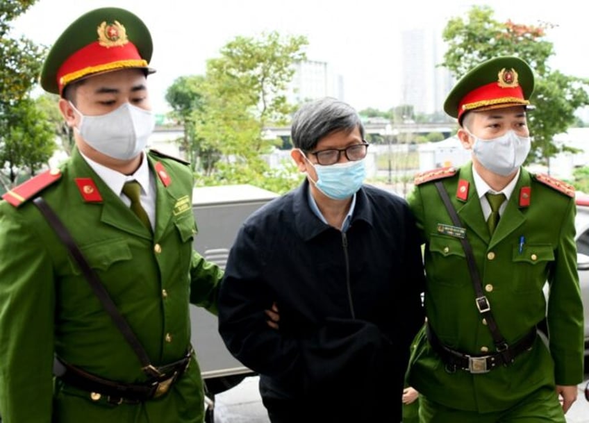 Vietnam's former minister of health Nguyen Thanh Long is led into court Wednesday by police