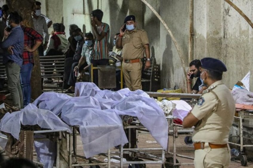 Police stand near the bodies of victims who died after a fire broke out at an amusement pa