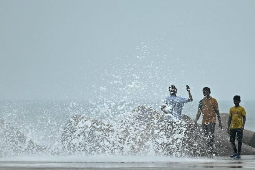 People walk through high tides at a fishing harbour in Chennai on November 27