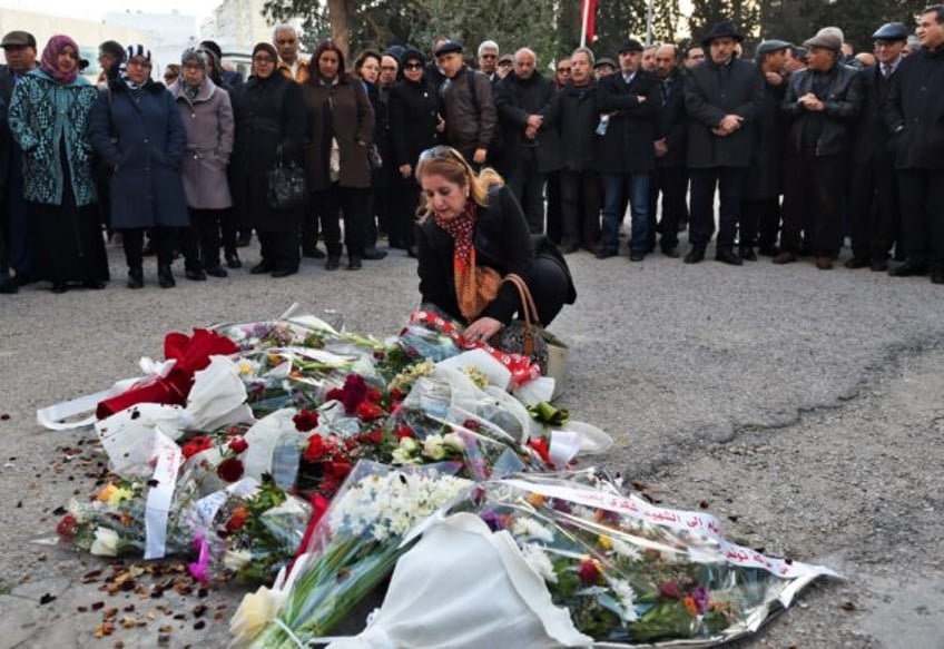 A Tunisian woman lays flowers at the site of the 2013 assassination of secular opposition