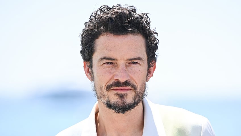 Orlando Bloom looks serious in a white jacket in Cannes