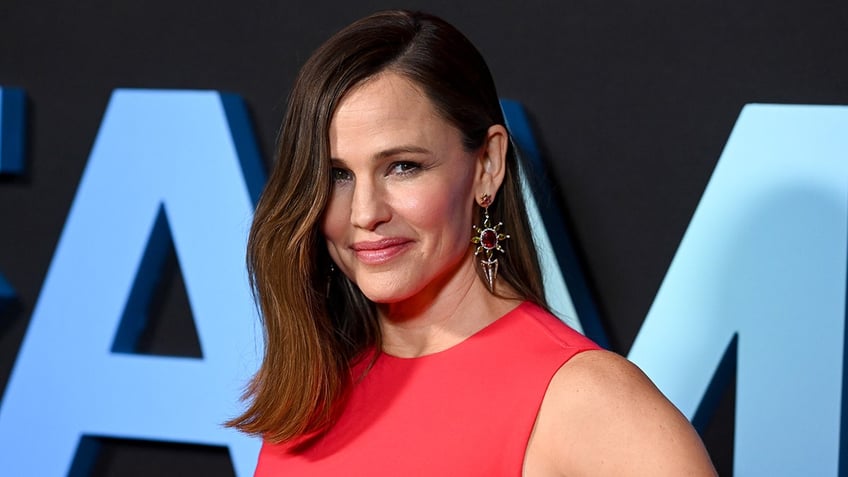 Jennifer Garner in a sleeveless red dress soft smiles on the carpet