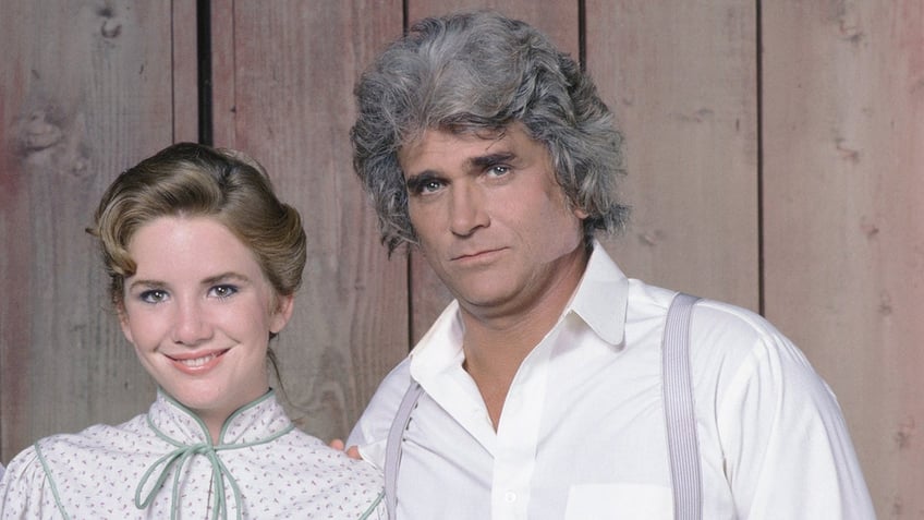 Melissa Gilbert smiles wearing a white blouse and green bow next to Michael Landon in a white shirt and purple suspenders in a photo from "Little House on the Prairie"