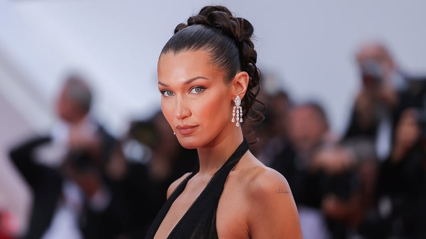 Bella Hadid in a black halter dress looks serious on the carpet with a pretty updo