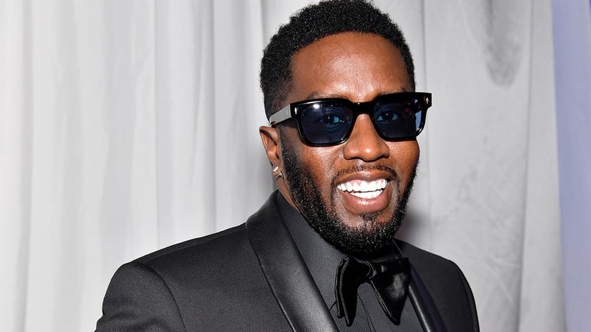 Sean Diddy Combs smiles in a black tuxedo with black sunglasses